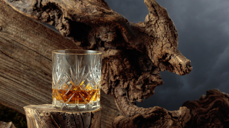Glass of whiskey in front of gnarled wood