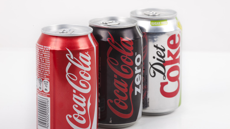 Three canned Coke products sitting together