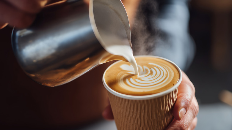 Milk being poured in a cup of coffee to make a latte