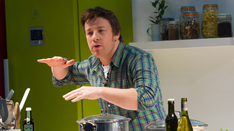 Jamie Oliver cooking in a kitchen while wearing a plaid shirt