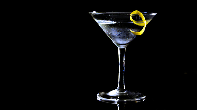 Martini with lemon twist on black background