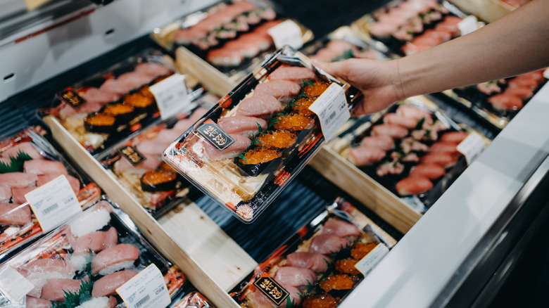 Hand holding a package of sushi in the grocery store