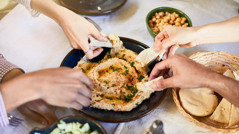 People eating hummus with pita bread