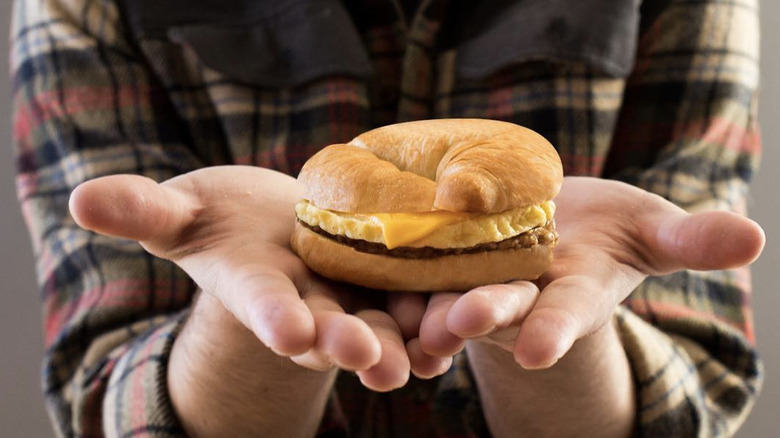 Hands holding a croissant sandwich