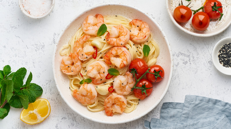 Cooked shrimp over pasta with fresh tomatoes and herbs