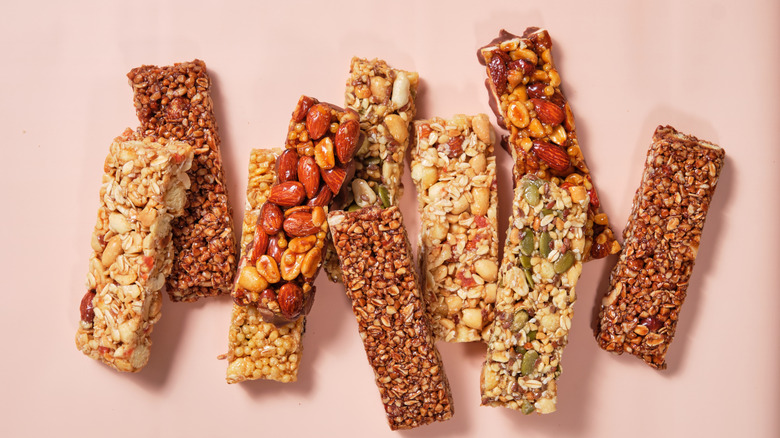 An assortment of protein bars laid out over a pink backdrop