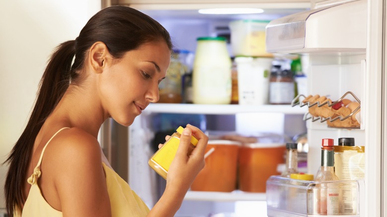 woman checking expiration date on a jar from the fridge