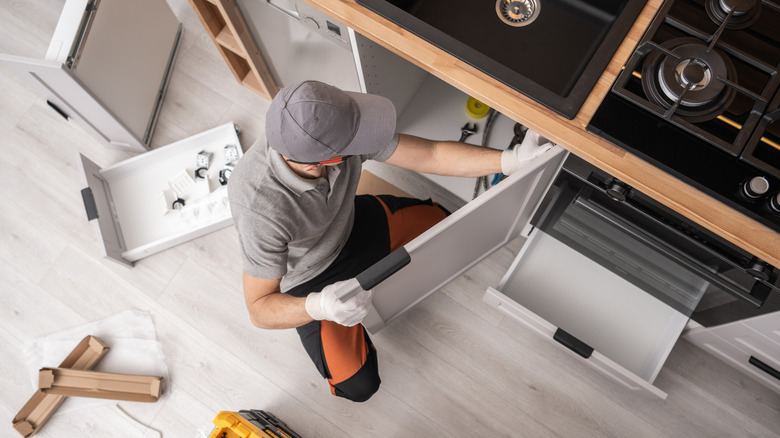 cabinetmaker installs kitchen cabinet