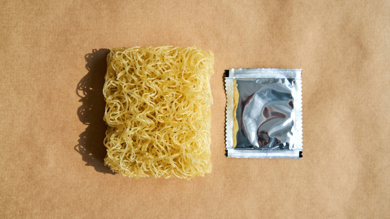 An uncooked instant ramen and a packet of seasoning sitting side by side