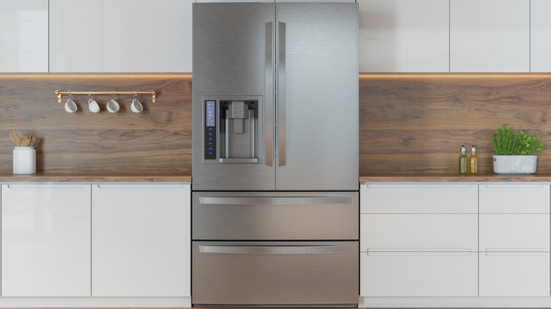 Stainless steel refrigerator in modern kitchen with white cabinets
