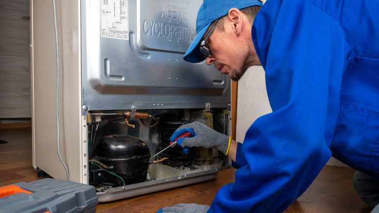 Man repairing the back panel of a refrigerator