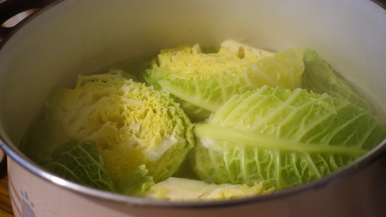 Three small cabbages floating in a boiling pot.
