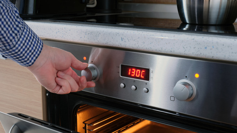 A cook setting the temperature on an oven