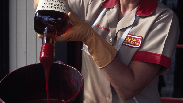 Woman dipping bottle in red wax