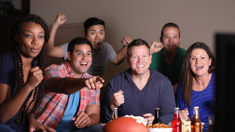 A group of friends is gathered around a television to celebrate the Super Bowl.