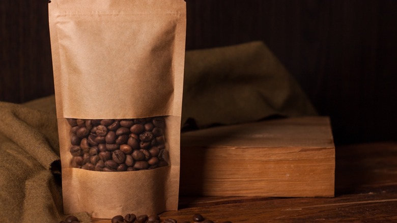 A brown paper bag full of coffee beans ready to be ground.