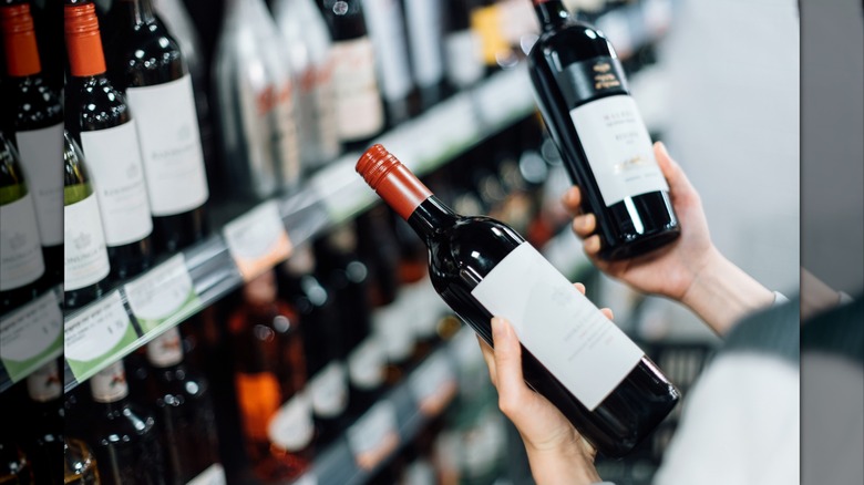 A person holding wine bottles at a store