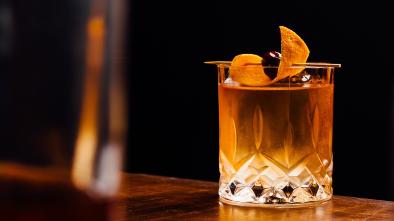 An old-fashioned cocktail with a cherry and orange peel