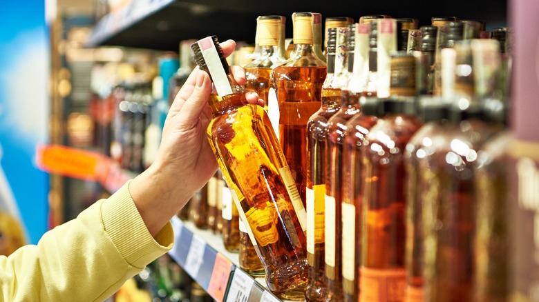 Picking a whiskey bottle from a store shelf
