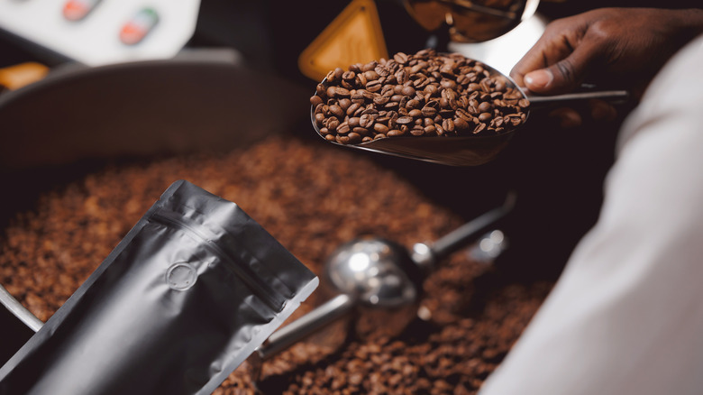 A hand packing a small pouch with coffee beans