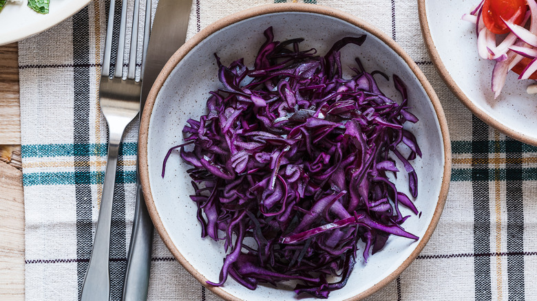 A bowl of red cabbage with a knife and fork next to it