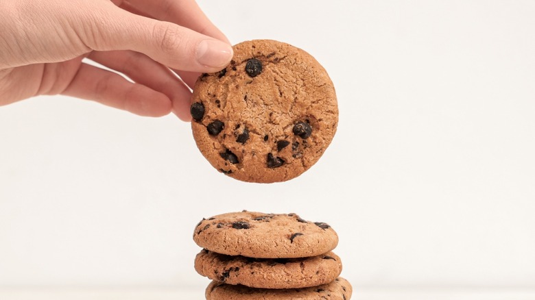 Close-up of a hand holding a golden-brown chocolate chip cookie