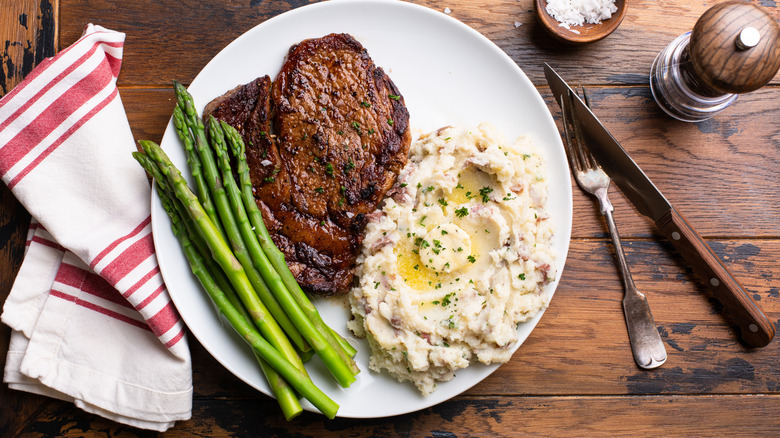 Steak served on a white plate with asparagus and mashed potatoes
