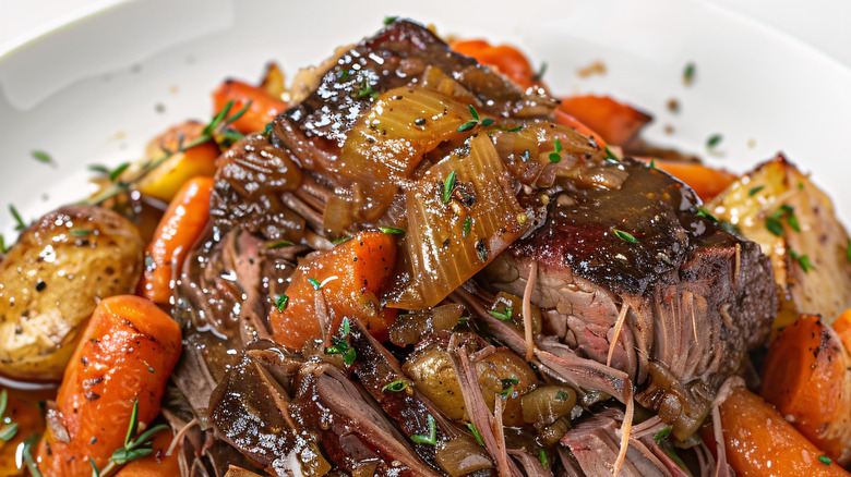 A heaped portion of classic American pot roast: tender beef, caramelized onions, cooked carrots, and potatoes.