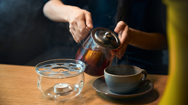An person pouring freshly brewed tea into a cup.