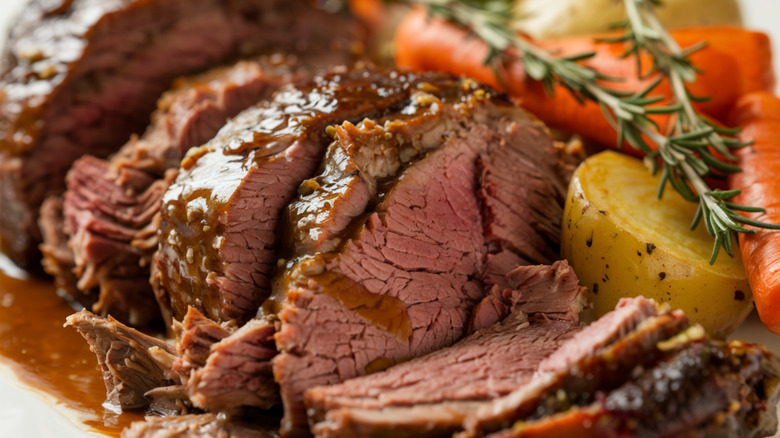 Close up of pot roast with potatoes, carrots, and rosemary sprigs