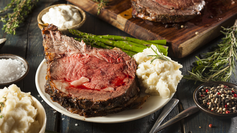 Prime rib is served with potatoes and asparagus
