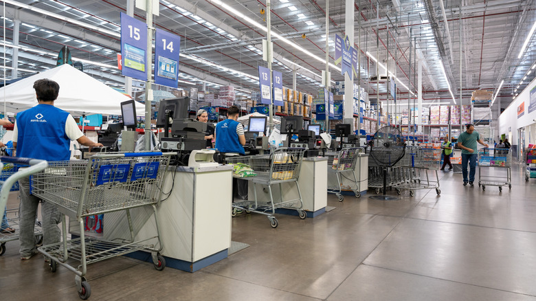 Checkout lanes at Sam's Club with active registers, customers, carts, clear signage, and bright open space
