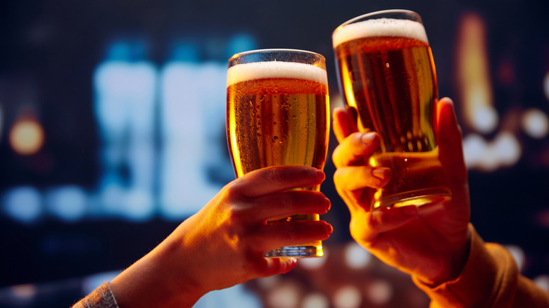 Two individuals toasting with glasses of beer.
