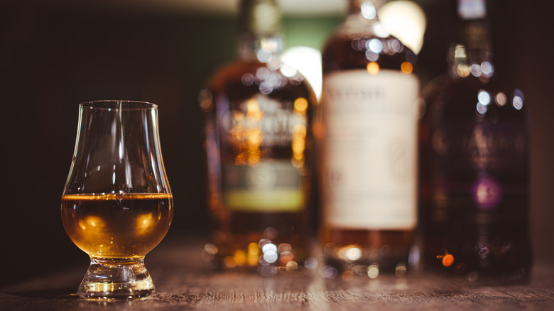 Glass of Scottish whisky with bottles in the background