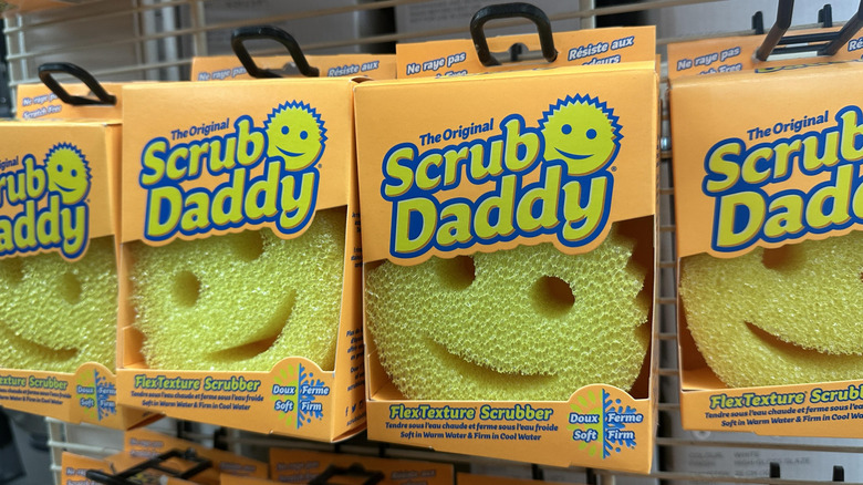A row of yellow Scrub Daddy scrubbers in a retail store.