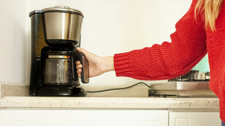 woman removing carafe from coffee maker