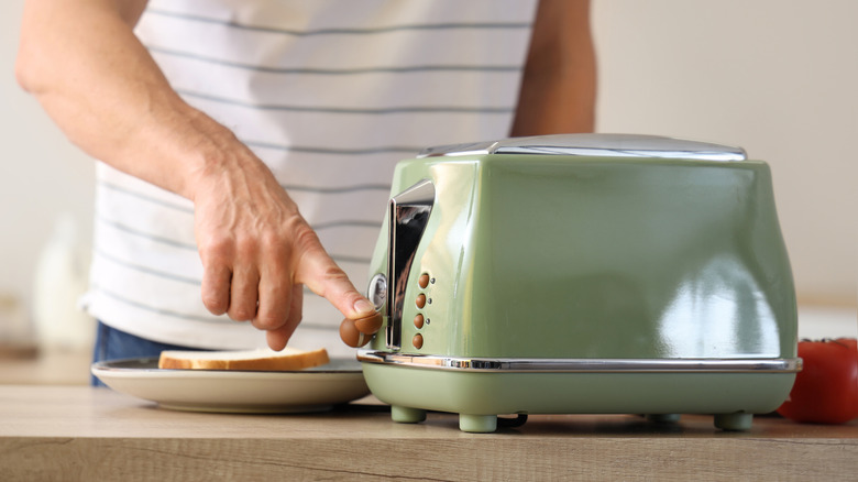 person using a green enamel toaster