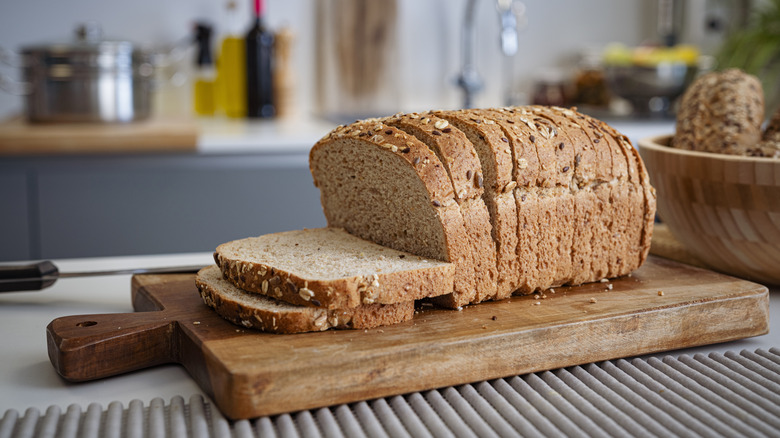 Sliced brown bread on a cutting board in a kitchen.