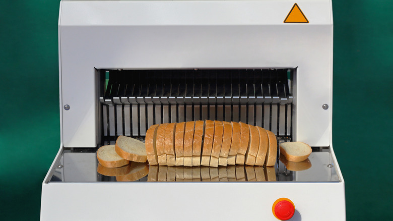 A sliced loaf of bread in front of a bread-slicing machine.