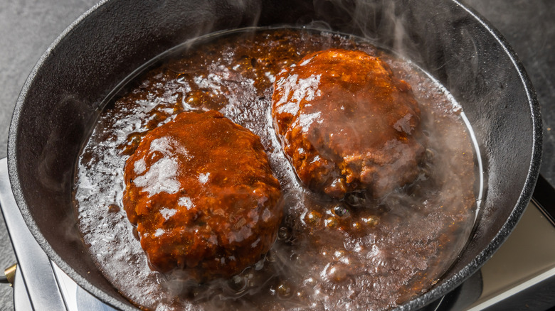 Two beef patties simmering in gravy.