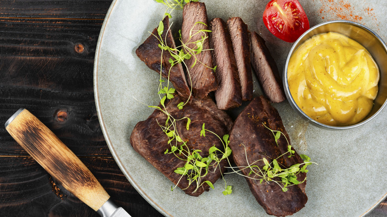 grilled ostrich steak with sauce and microgreens