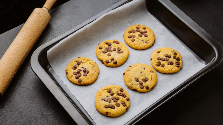 A tray of chocolate chip cookies on parchment baking paper.