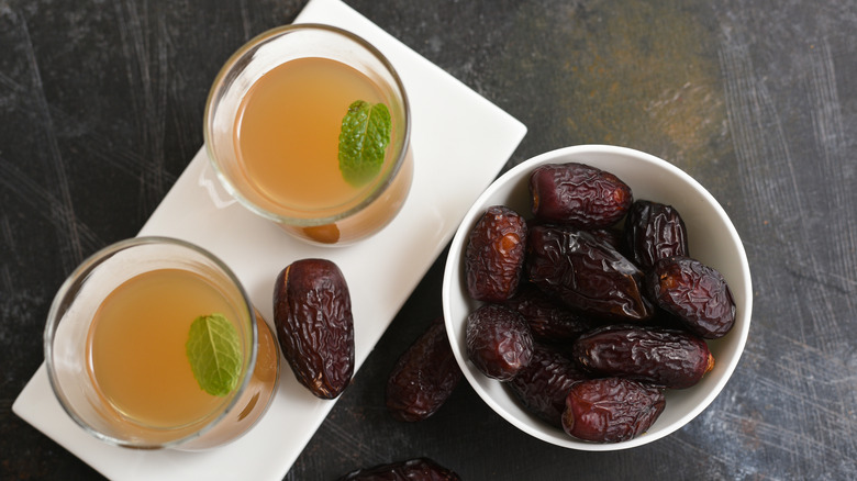 A Saudi Arabian coffee, a pale yellow color, next to a bowl of Medjool dates