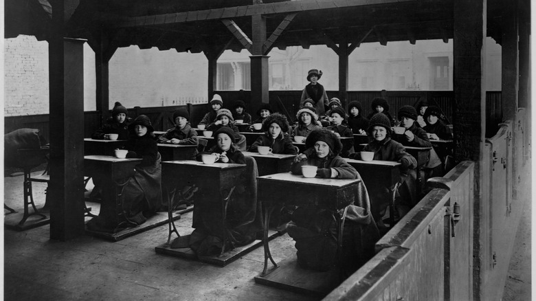 Students eating soup at their desks in the 1900s