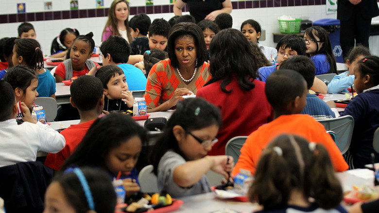 First Lady Michelle Obama sits in a cafeteria eating lunch with students