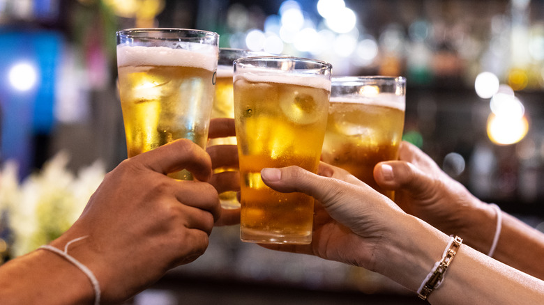 People holding up beer glasses to cheers