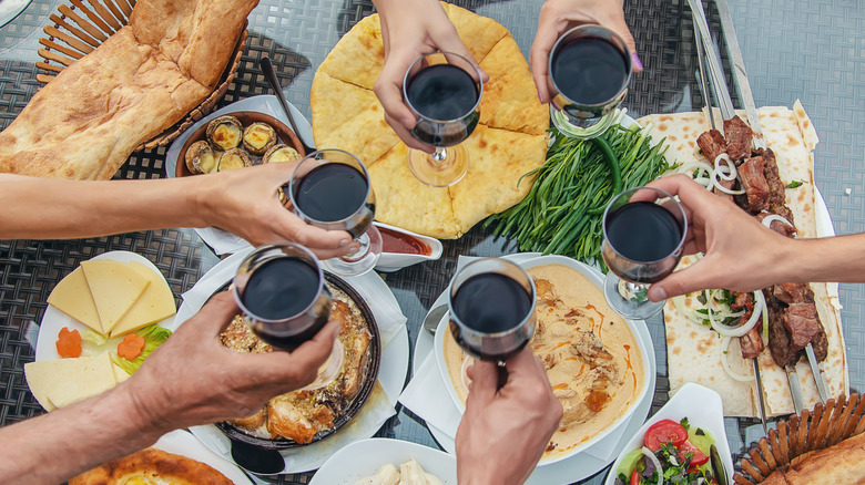 People toasting with wine glasses over a typical Georgian meal