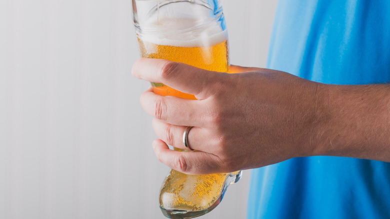 Hand holds full glass beer boot