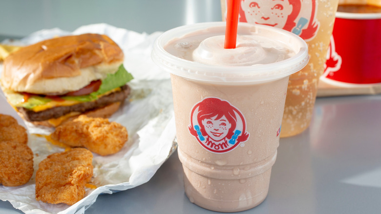 A Wendy's Frosty in front of burgers and chicken nuggets at Wendy's