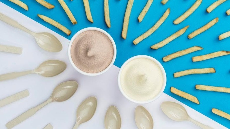 A Chocolate Frosty and Vanilla Frosty from Wendy's on a table with spoons and fries